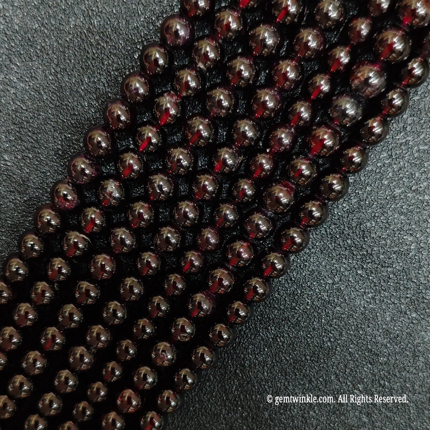 multiple strands of polished red garnet crystal beads on black background