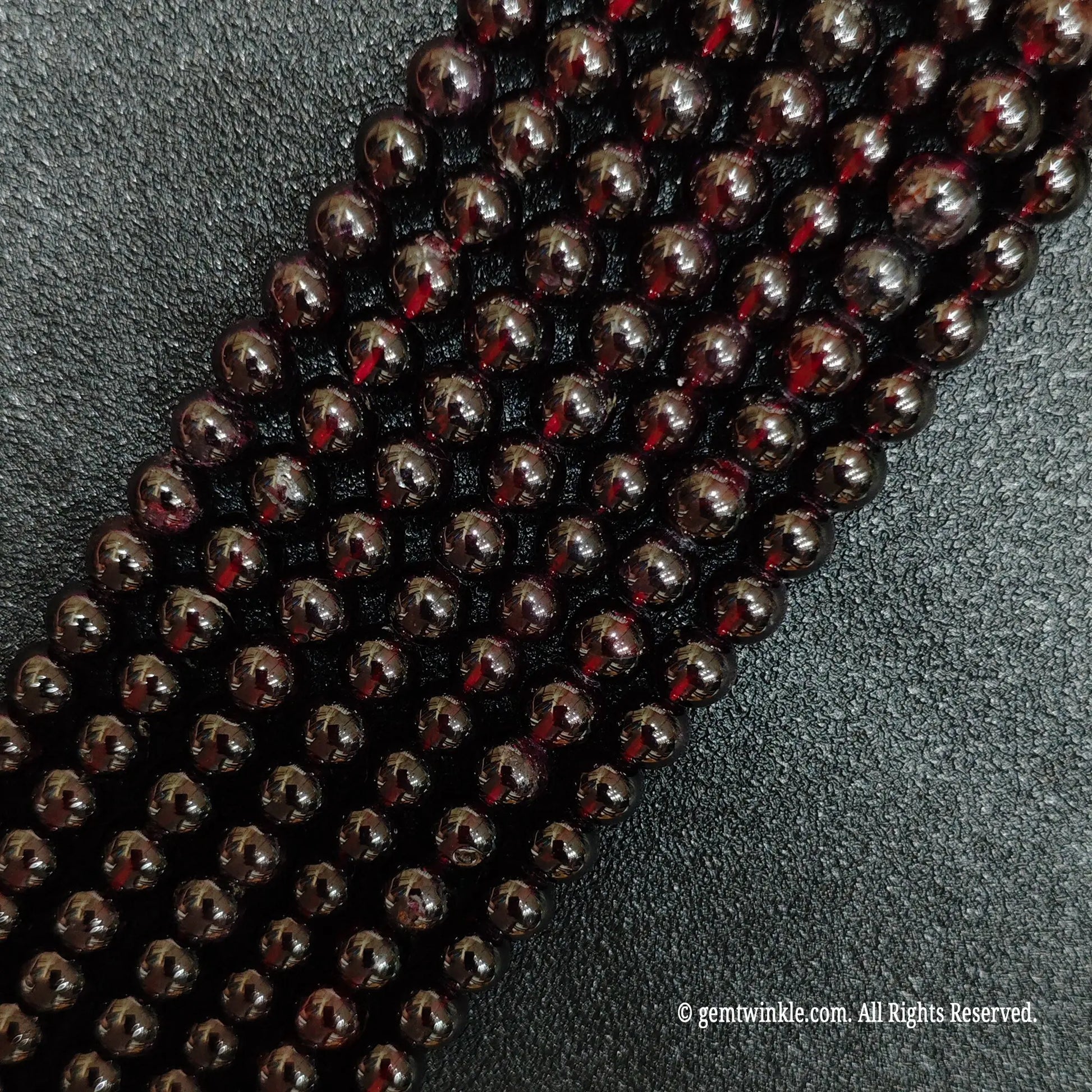 multiple strands of polished red garnet crystal beads on black background