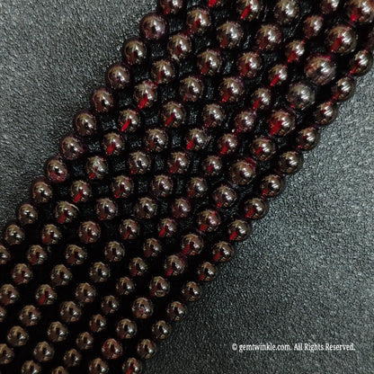 multiple strands of polished red garnet crystal beads on black background
