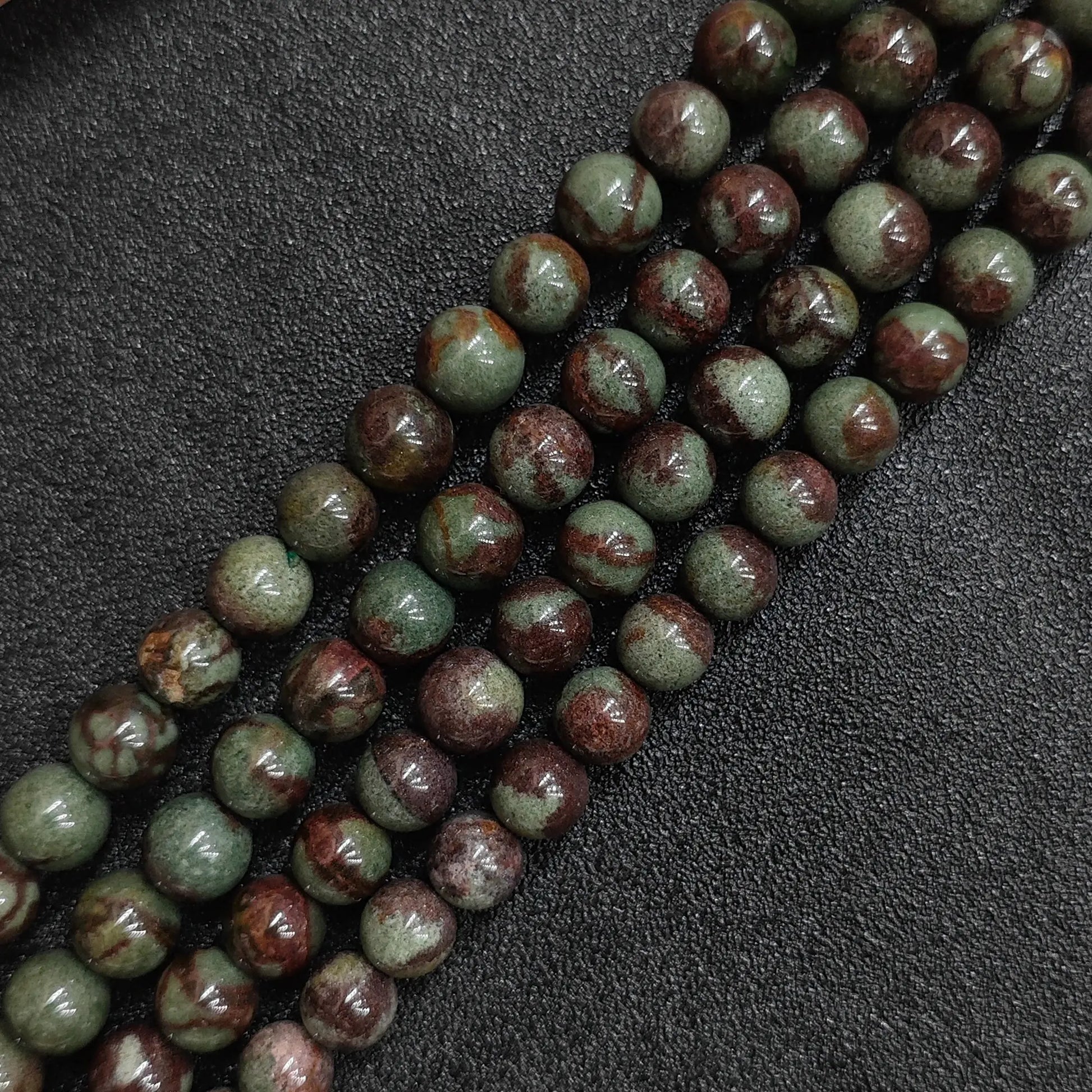 multiple loose strands of green ghost quartz crystal beads arranged on black surface