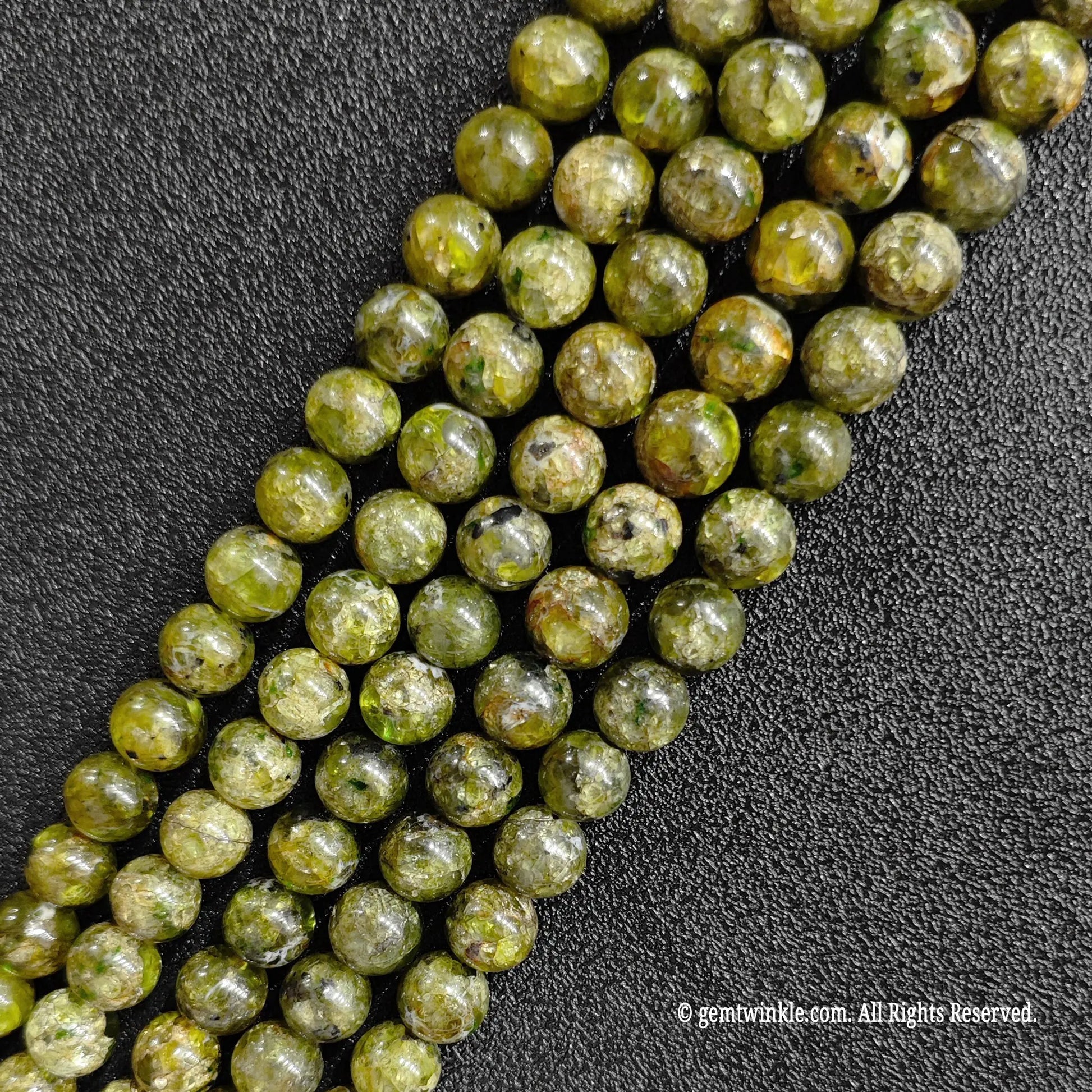 multiple strands of genuine grade c peridot crystal beads laid out on black background