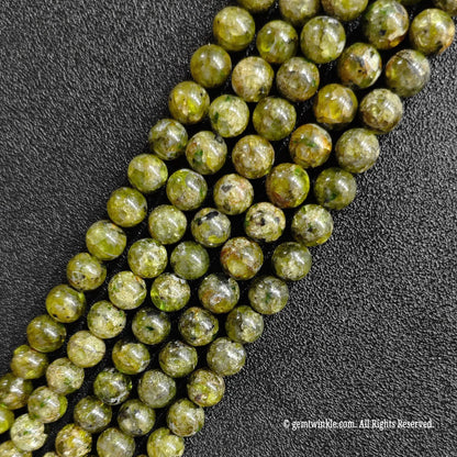 multiple strands of genuine grade c peridot crystal beads laid out on black background