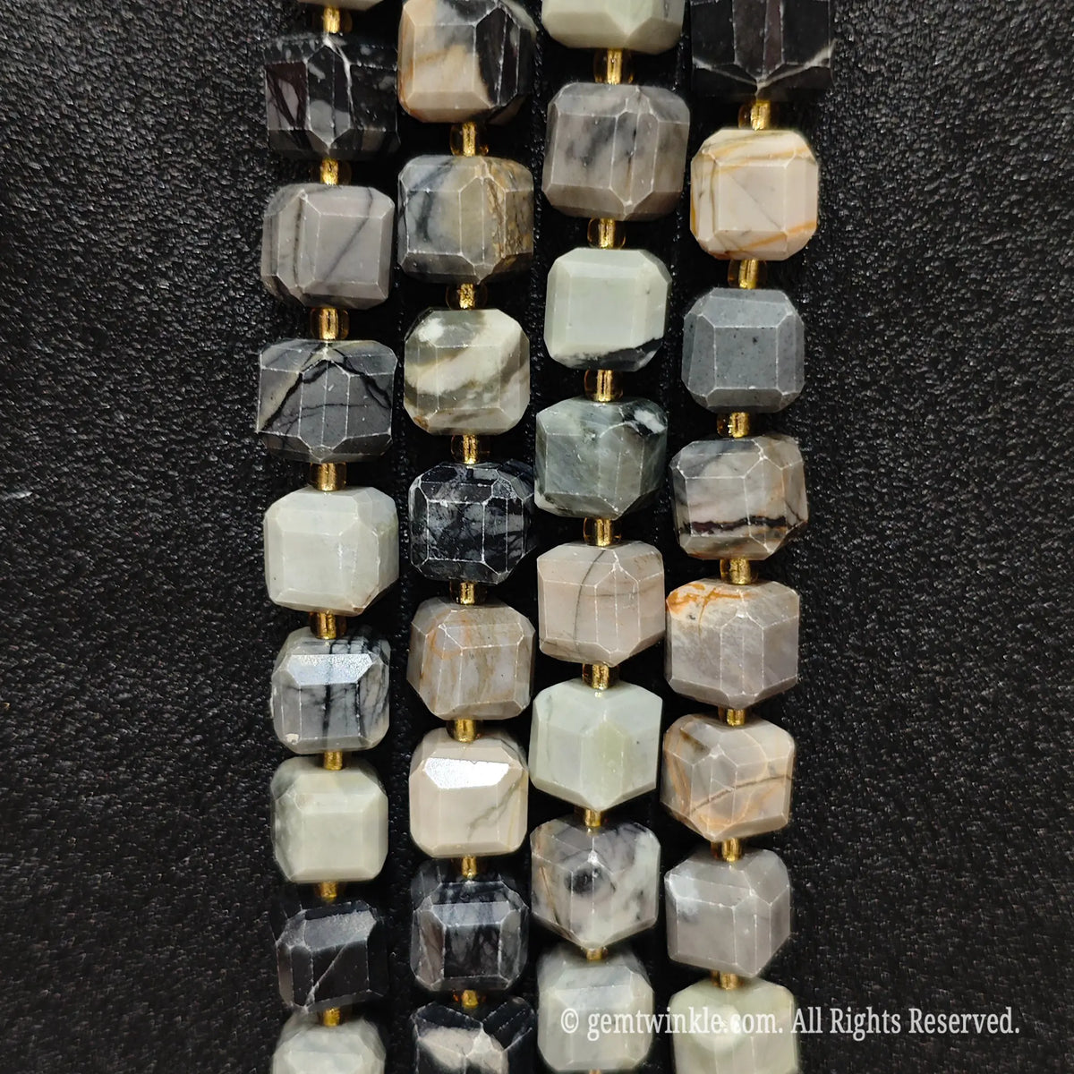 Angled presentation of picasso stone strands showing their smooth polished finish and clean drill holes