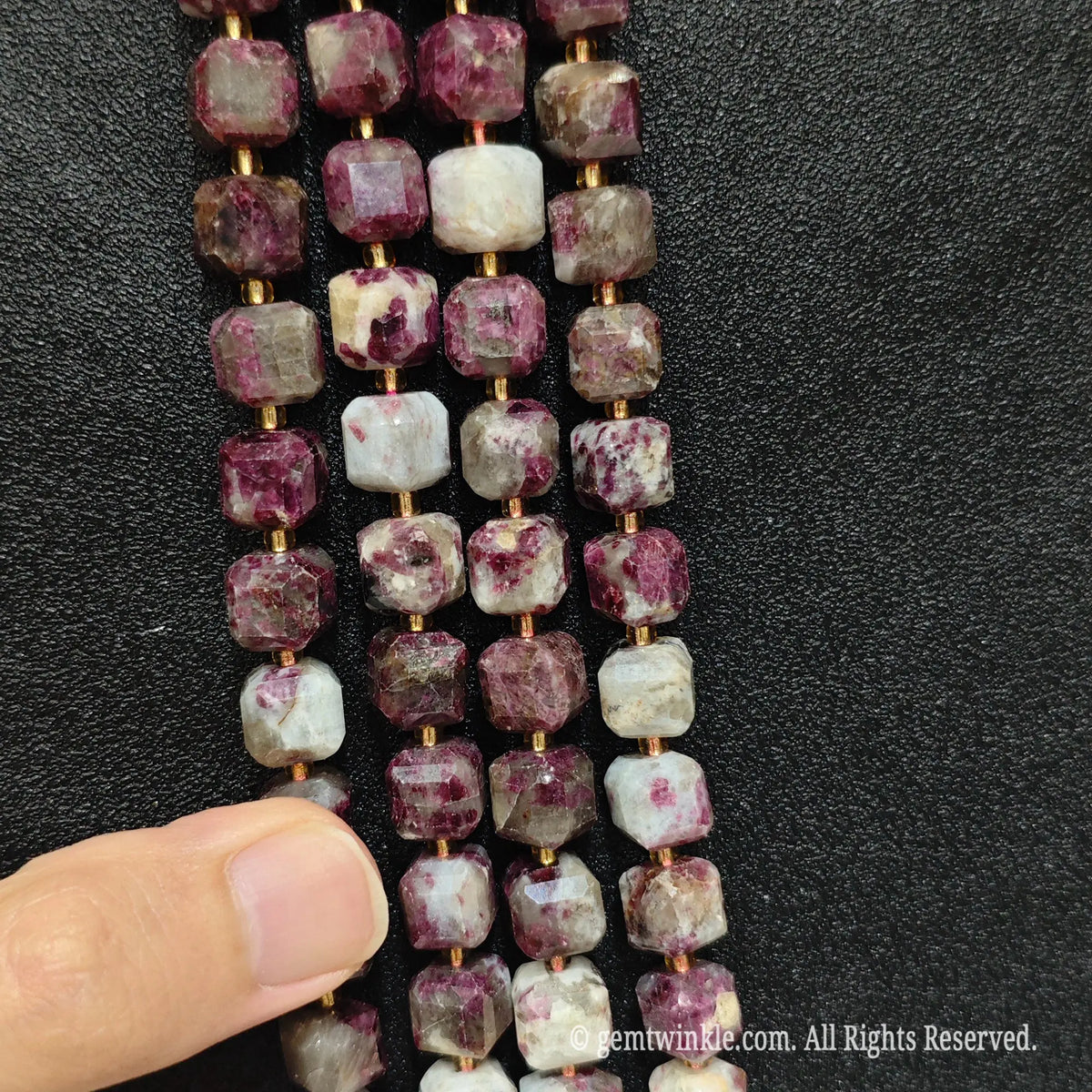 Angled view of polished plum blossom tourmaline square beads highlighting clean center drill holes