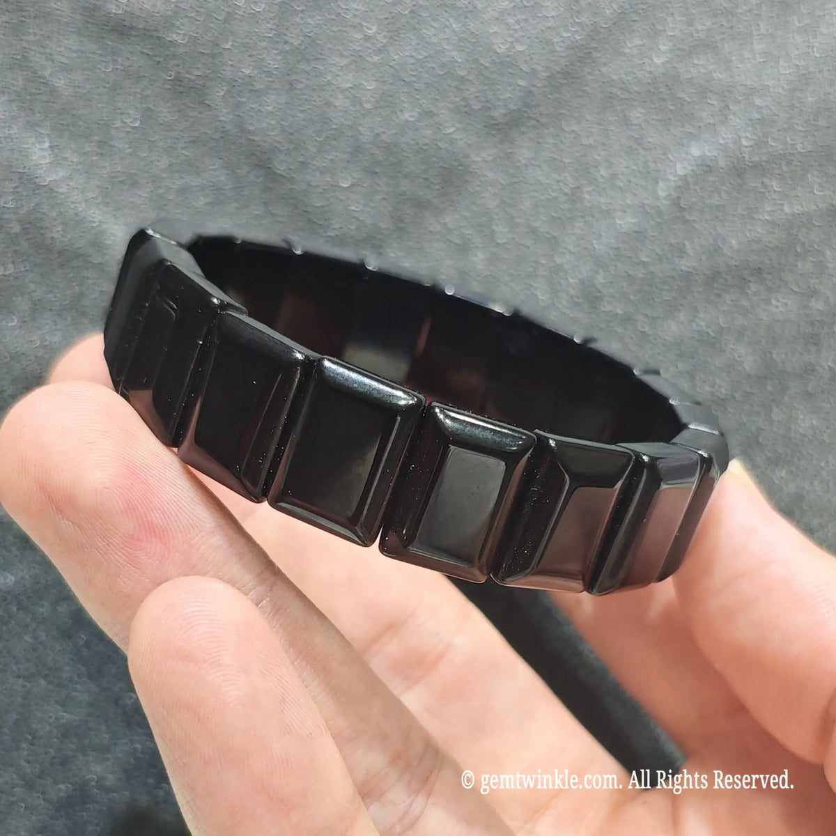 Close up view of glossy volcanic glass flat bead band showing polished geometric bead construction