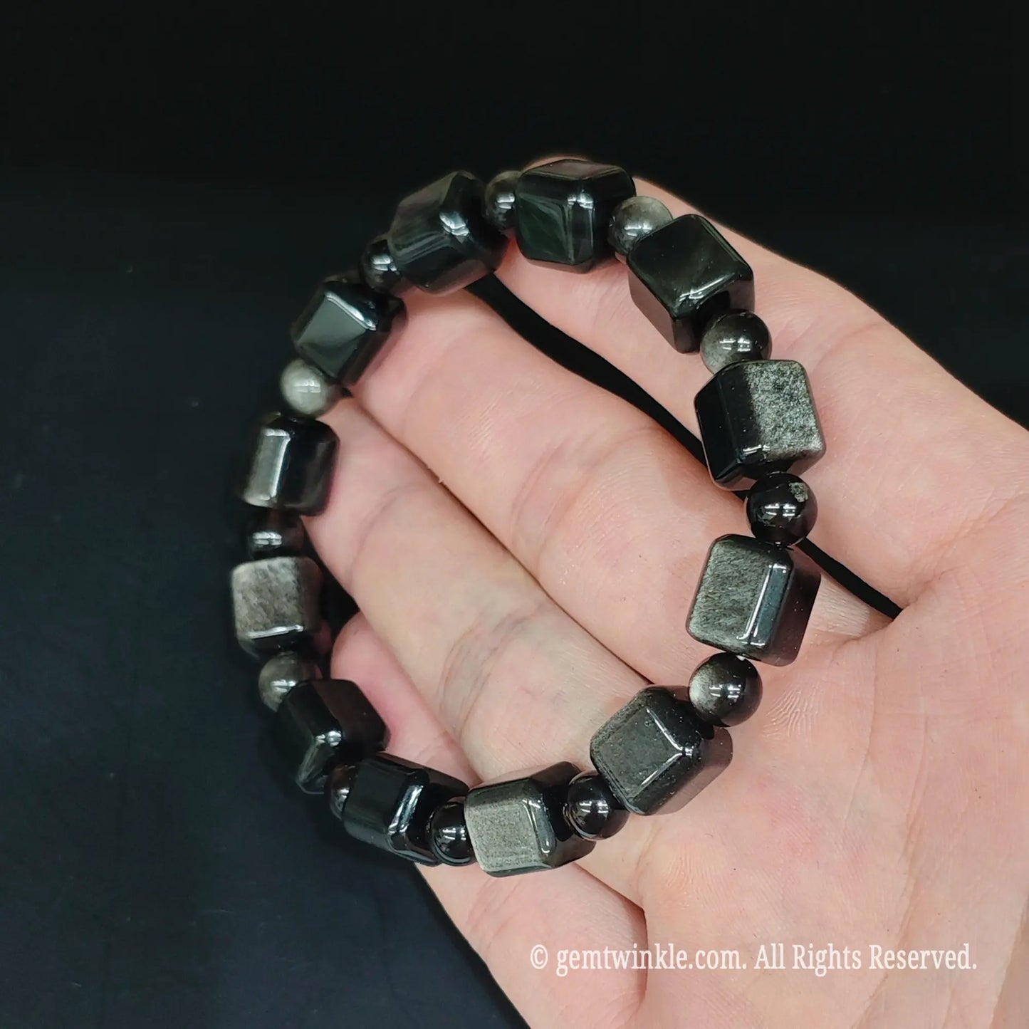 Full view of glossy silver sheen obsidian 10mm cube bead bracelet open on hand showing uniform bead shaping