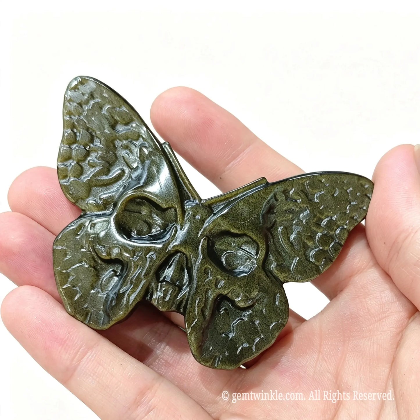 Front view of gold obsidian death hawkmoth butterfly sculpture in hand displaying carved wing textures