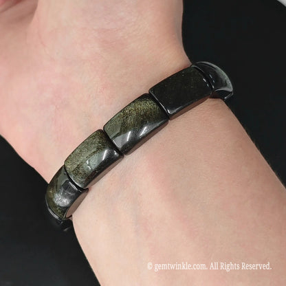 Gold sheen obsidian 16mm plate bead stretch bangle bracelet styled on wrist under natural indoor light