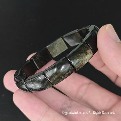 Angle view of gold sheen obsidian geometric plate cuff bracelet highlighting polished curved glass plates