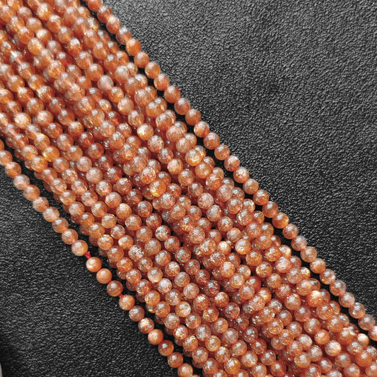 Macro closeup of natural golden sunstone B plus grade 4mm smooth round beads showing intense copper sparkle