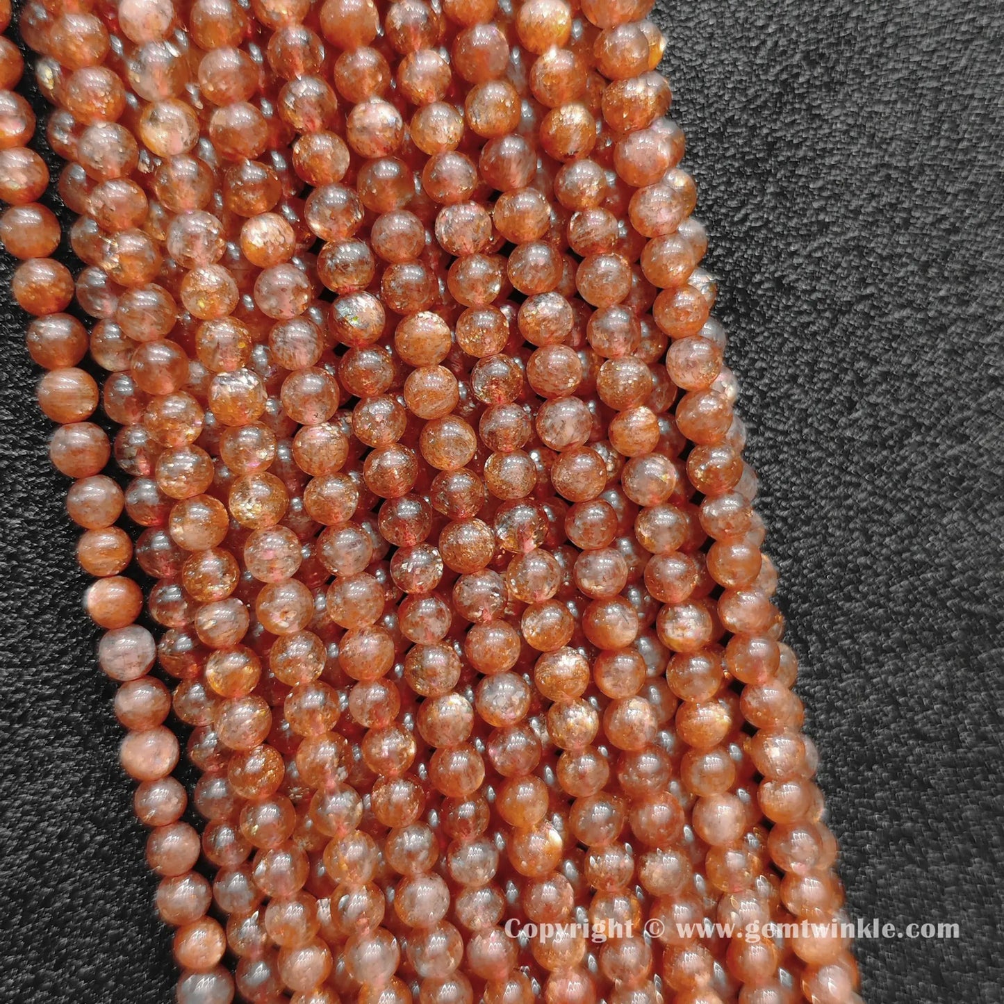 Perspective view of B plus grade golden sunstone 4mm round beads displaying uniform polish and glitter