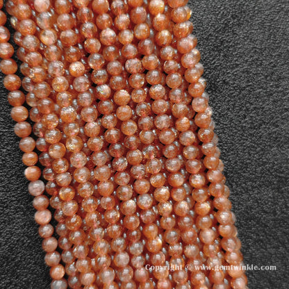 Perspective view of B plus grade golden sunstone 4mm round beads displaying uniform polish and glitter