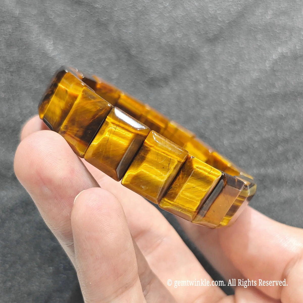Side view of a golden tiger eye bar cut band displaying rich amber and honey brown light reflection