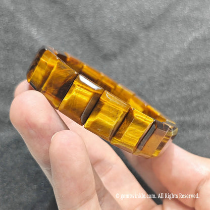 Side view of a golden tiger eye bar cut band displaying rich amber and honey brown light reflection
