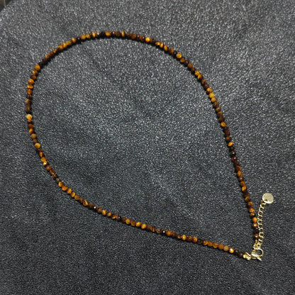 Hand holding 3mm micro faceted Golden Tiger Eye necklace strand showing silky golden brown cat eye chatoyancy