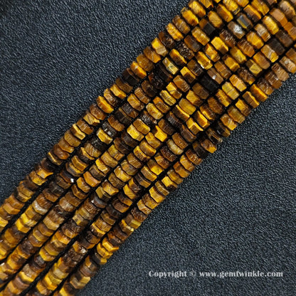 Angled view of natural golden tiger eye faceted disc gemstone strands arranged parallel on dark background