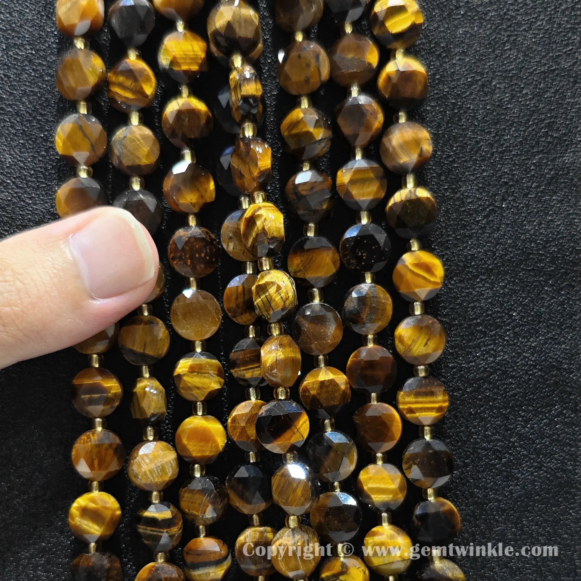 Hand holding strands of 8mm and 10mm golden tiger eye hexagram flat disc beads
