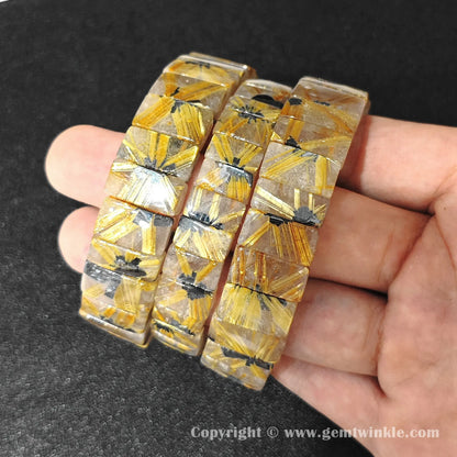 multiple natural golden rutilated quartz plate bracelets displayed together for customer selection