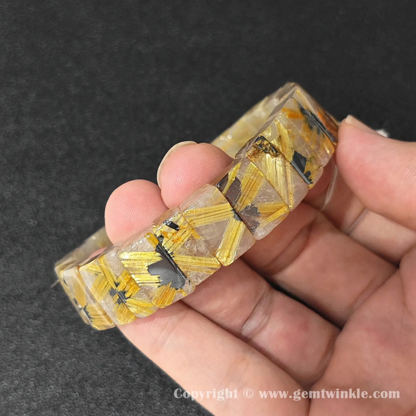 angled view of natural golden rutilated quartz bangle cuff bracelet held in hand showing 16-17cm fit