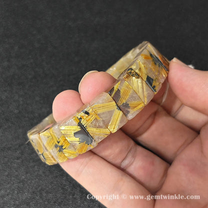 angled view of natural golden rutilated quartz bangle cuff bracelet held in hand showing 16-17cm fit