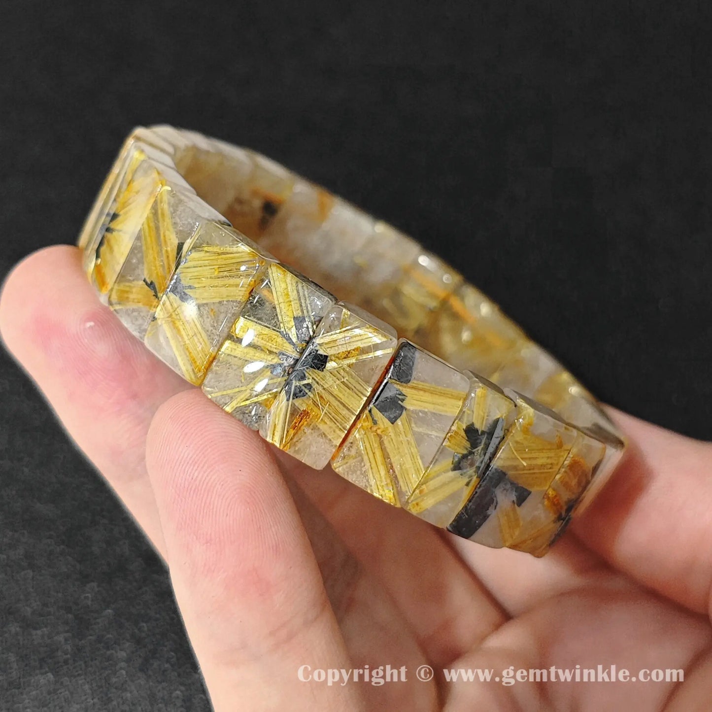 close up view of golden titanium rutile needles inside clear quartz plate beads