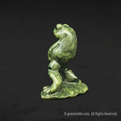 Full side profile view of a goofy serpentine peeing toad sculpture showing its smooth polished green yellow mineral texture