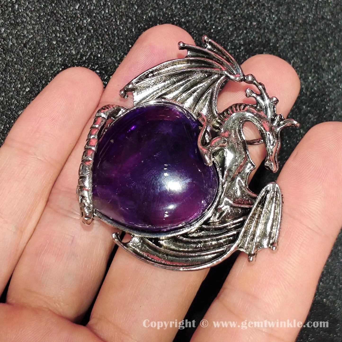 Angled view of 5cm gothic alloy dragon wrapped heart amethyst pendant on hand