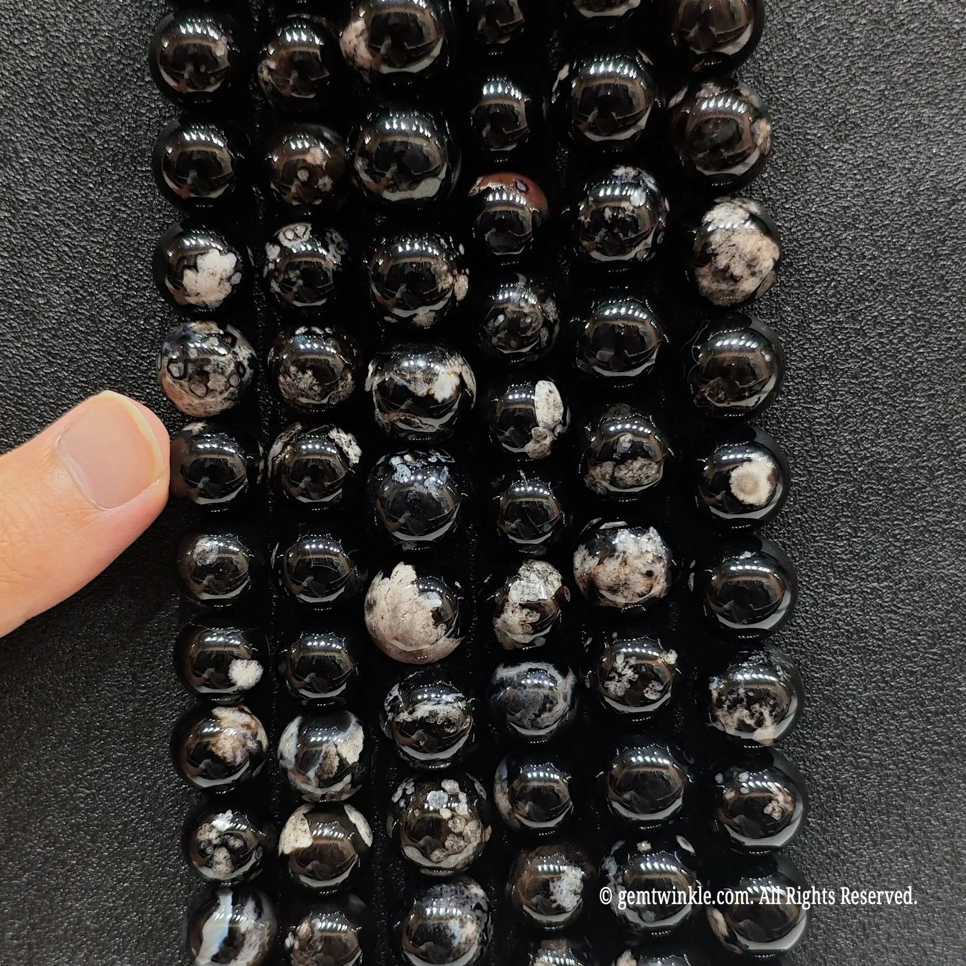 Vertical view of gothic style dyed sakura agate crystal beads highlighting surface polish and round cut over an agate base
