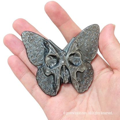 Front view of gothic silver sheen obsidian skull moth figurine 8x5cm resting in hand