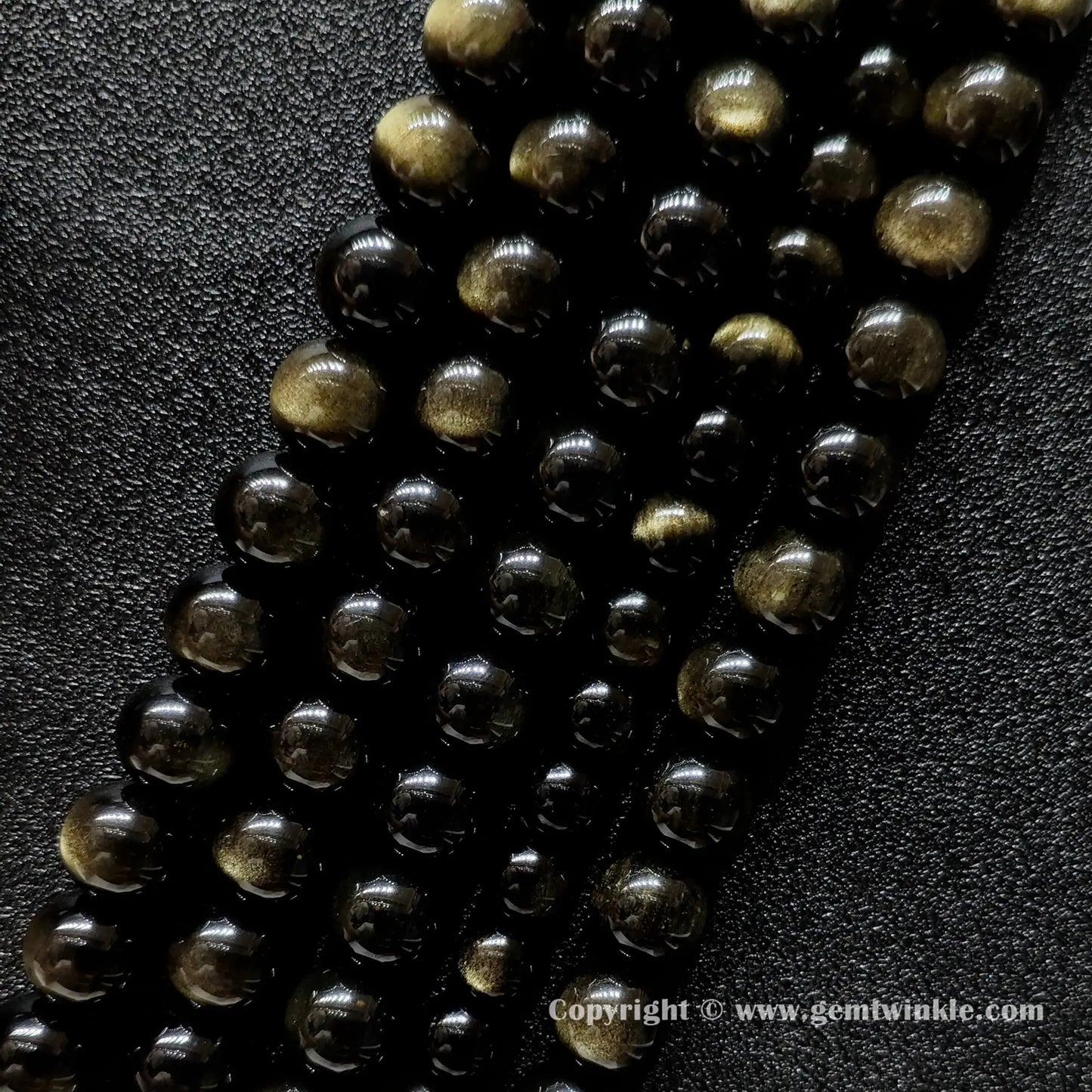 Angled view of Grade A gold sheen obsidian gemstone strands with smooth polish