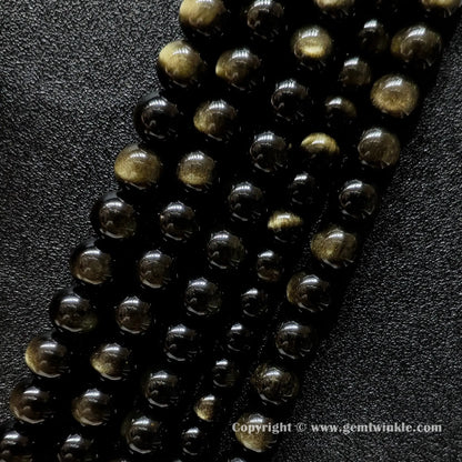 Angled view of Grade A gold sheen obsidian gemstone strands with smooth polish