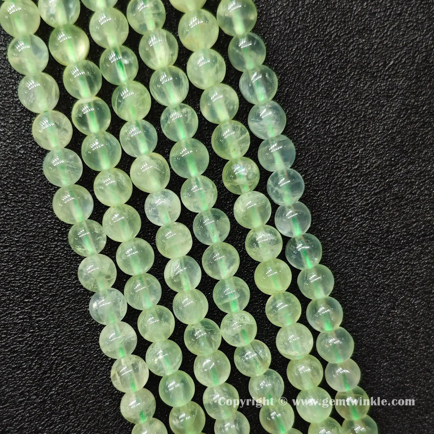 Perspective view of Grade A green prehnite round beads showing polished surface finish across sizes