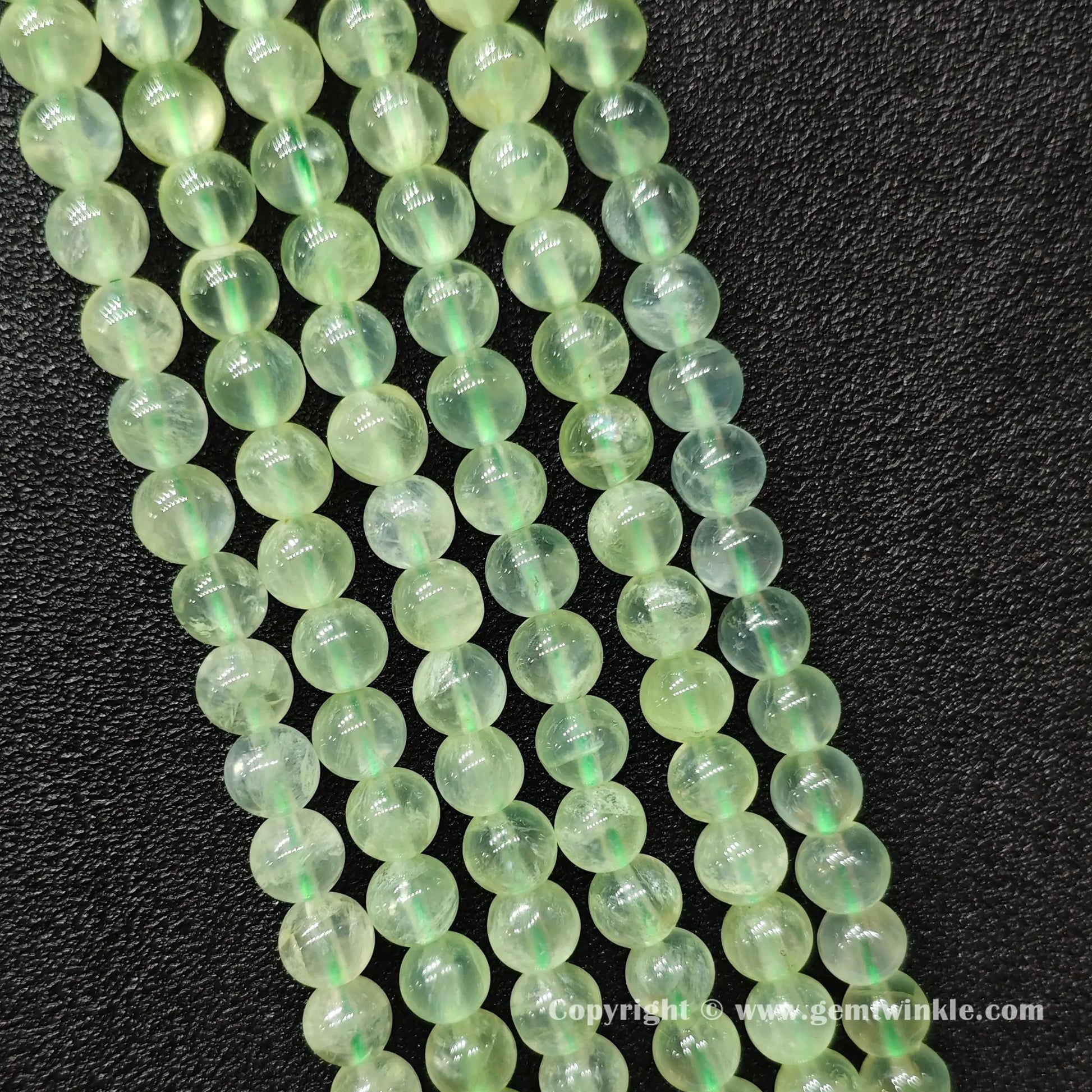 Perspective view of Grade A green prehnite round beads showing polished surface finish across sizes