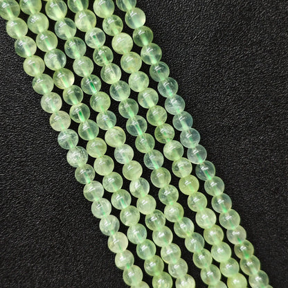 Macro closeup of Grade A clean prehnite smooth round beads showing translucent green body free of black spots