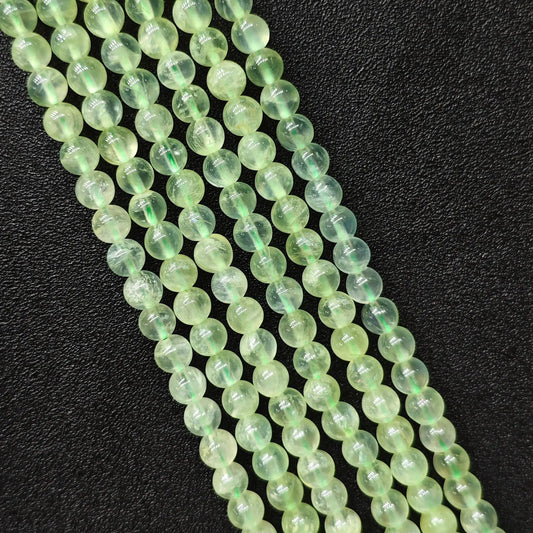 Macro closeup of Grade A clean prehnite smooth round beads showing translucent green body free of black spots