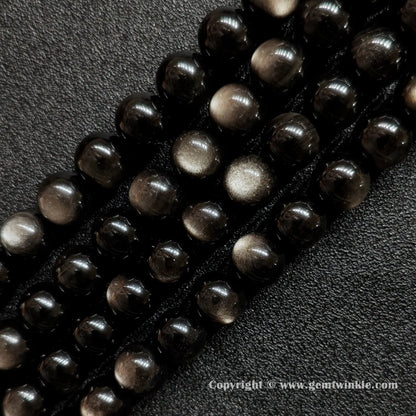 Angled view of Grade A silver sheen obsidian gemstone strands highlighting smooth polish and silver reflections