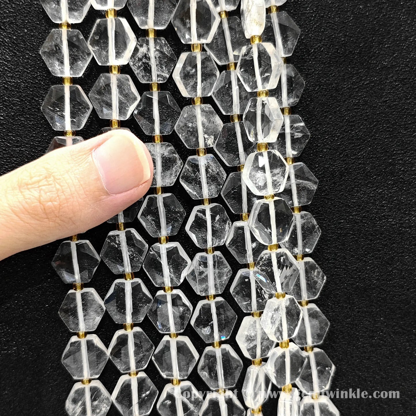 Hand holding 12mm natural clear quartz hexagon flat coin beads strand
