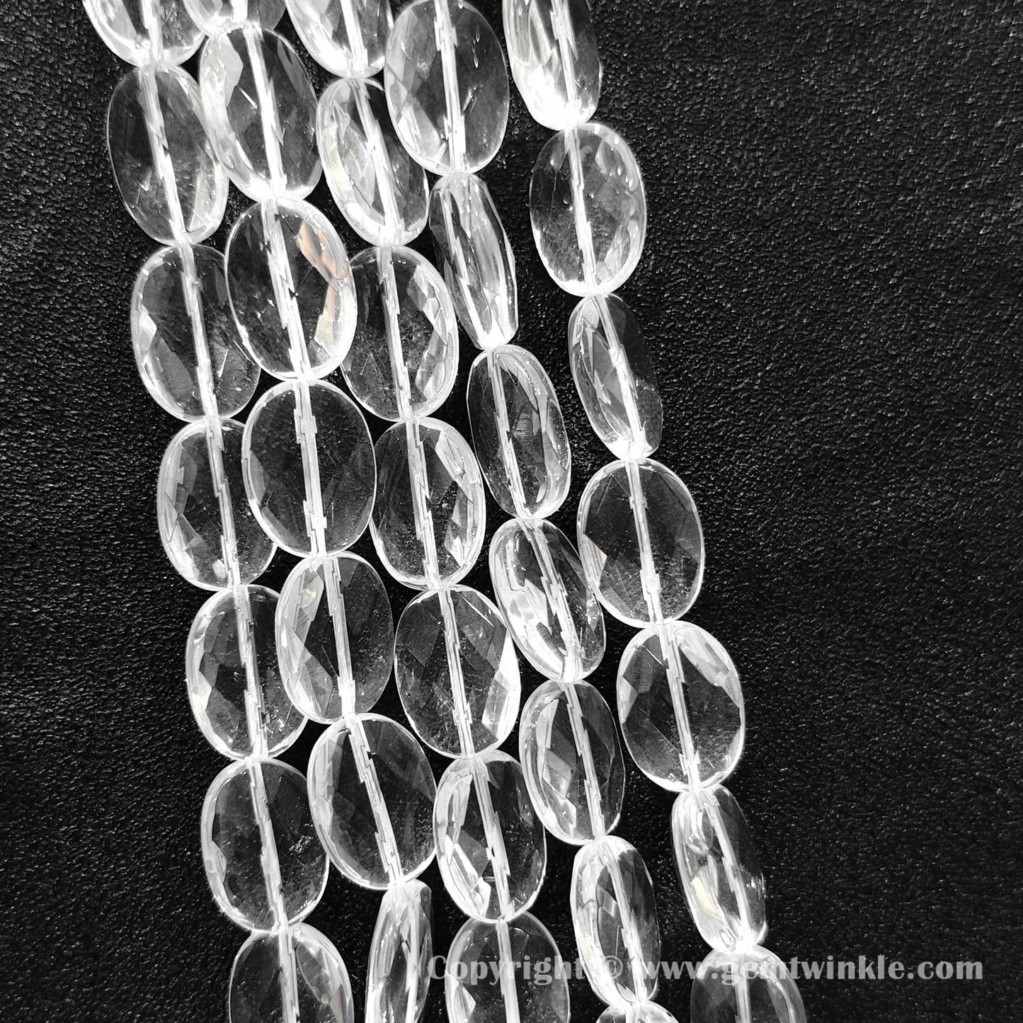 Hand holding 13mm natural clear quartz faceted oval flat beads strand