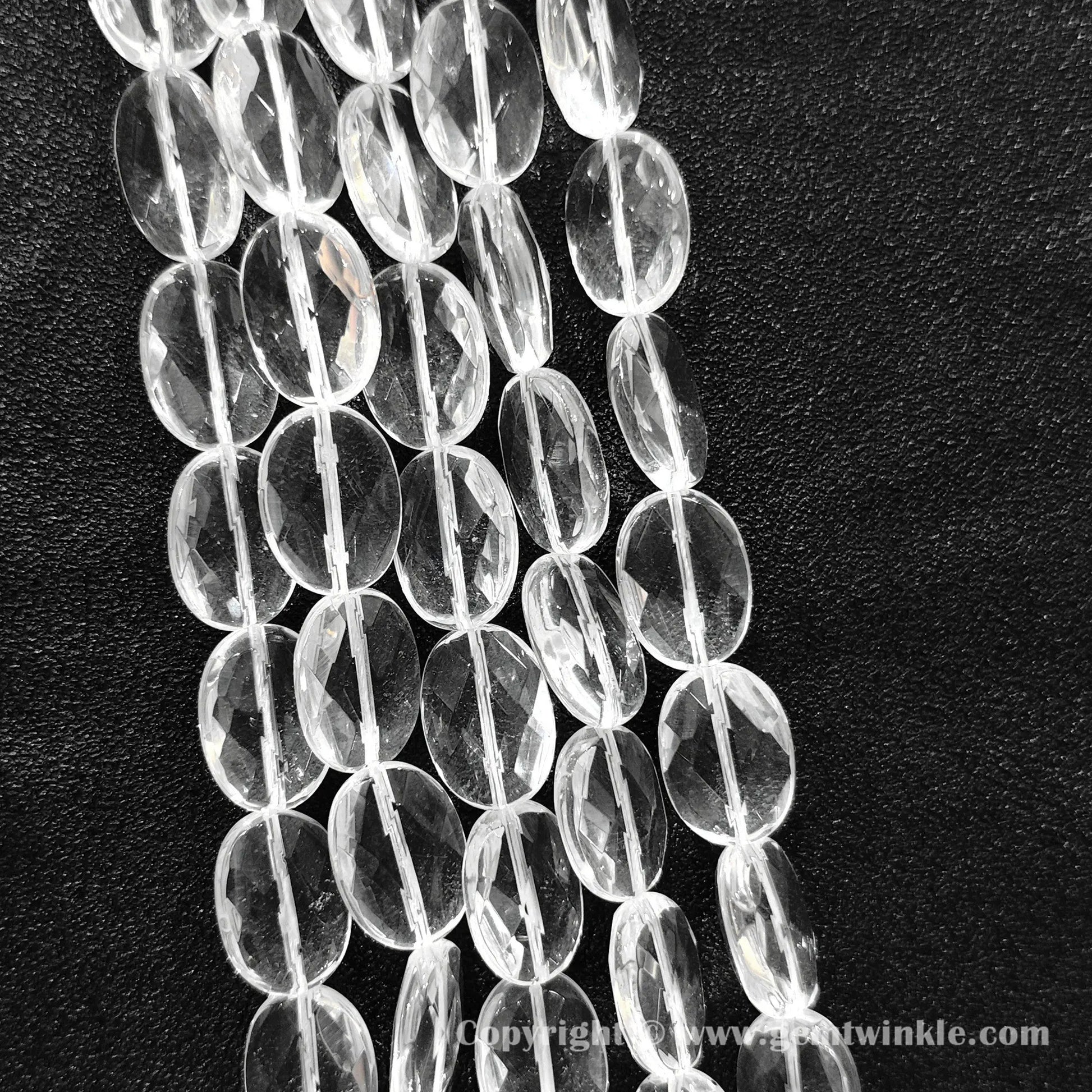 Hand holding 13mm natural clear quartz faceted oval flat beads strand