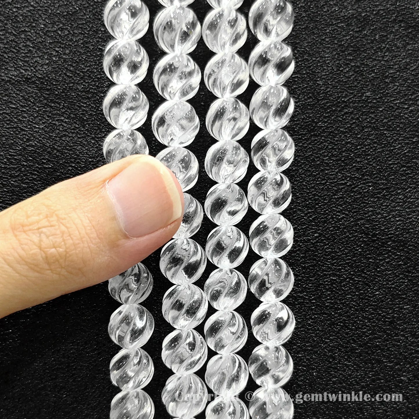 Hand holding 10mm natural clear quartz spiral twist beads strand