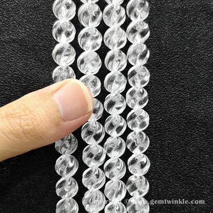 Hand holding 10mm natural clear quartz spiral twist beads strand
