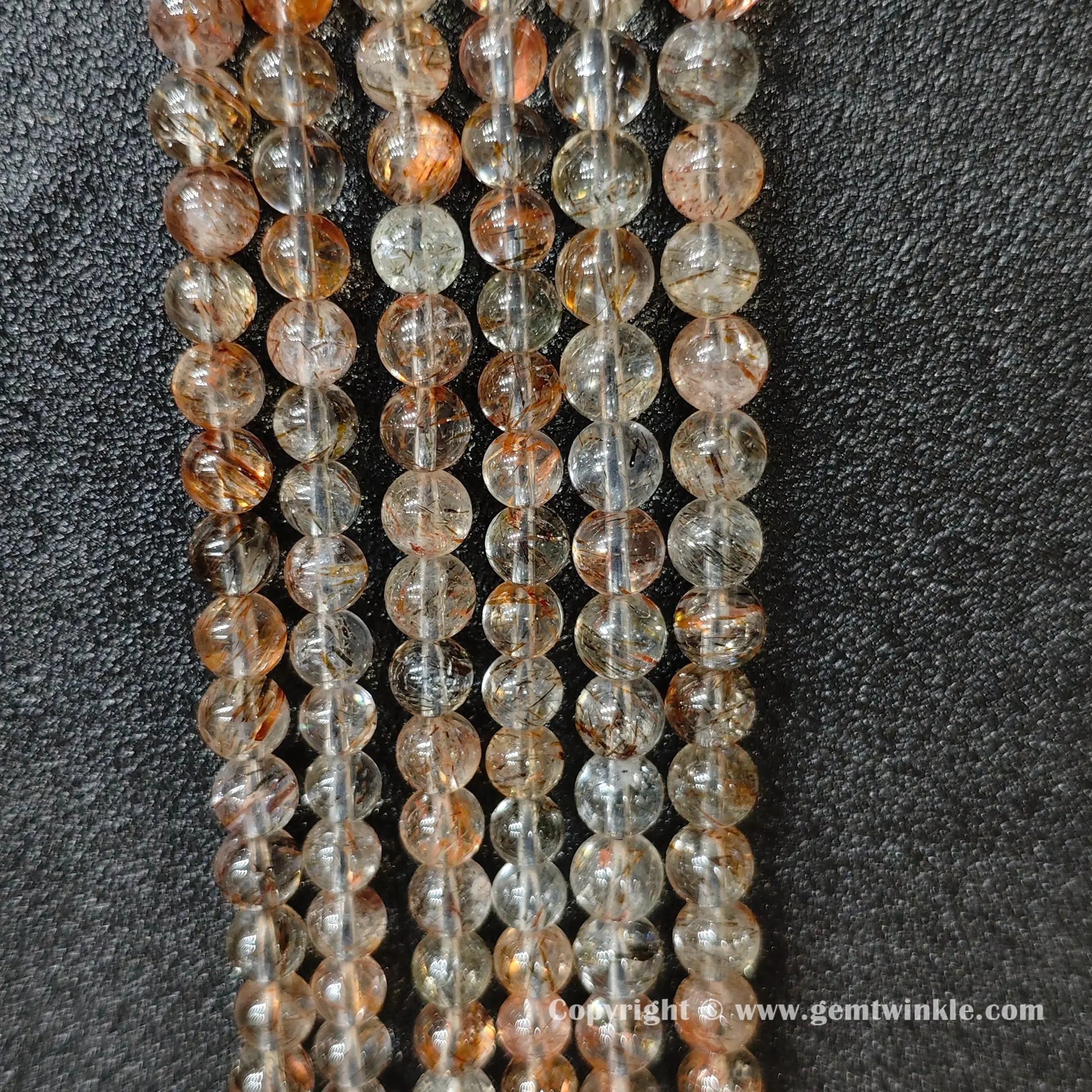 Perspective view of Grade B black gold super seven quartz round beads showing polished surface across 3mm to 6mm