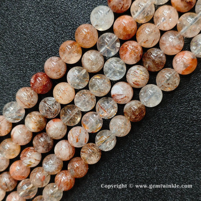 Angled view of Grade C black gold super seven round bead strands laid parallel on dark surface