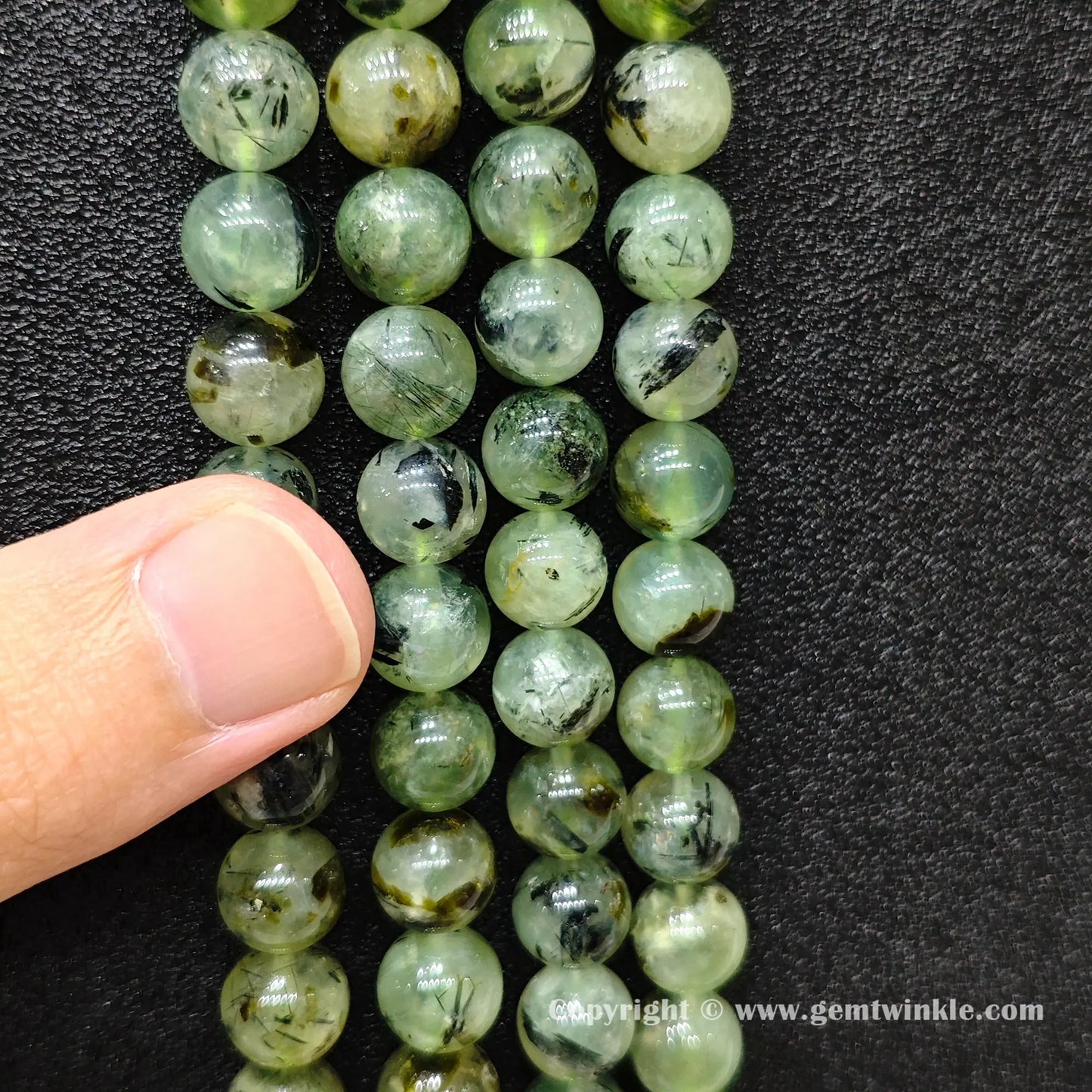Perspective view of Grade C green prehnite round beads showing polished surface across 4mm to 10mm sizes