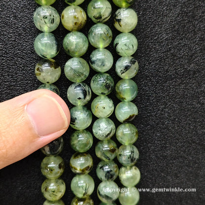 Perspective view of Grade C green prehnite round beads showing polished surface across 4mm to 10mm sizes