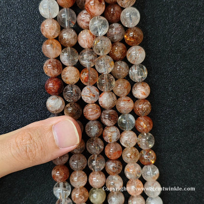 Close up view of Grade C black gold super seven round beads held on hand for natural color variation preview