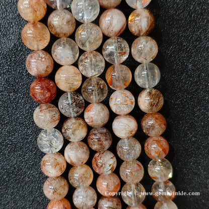 Perspective view of Grade C black gold super seven quartz round beads showing polished surface across 4mm to 12mm
