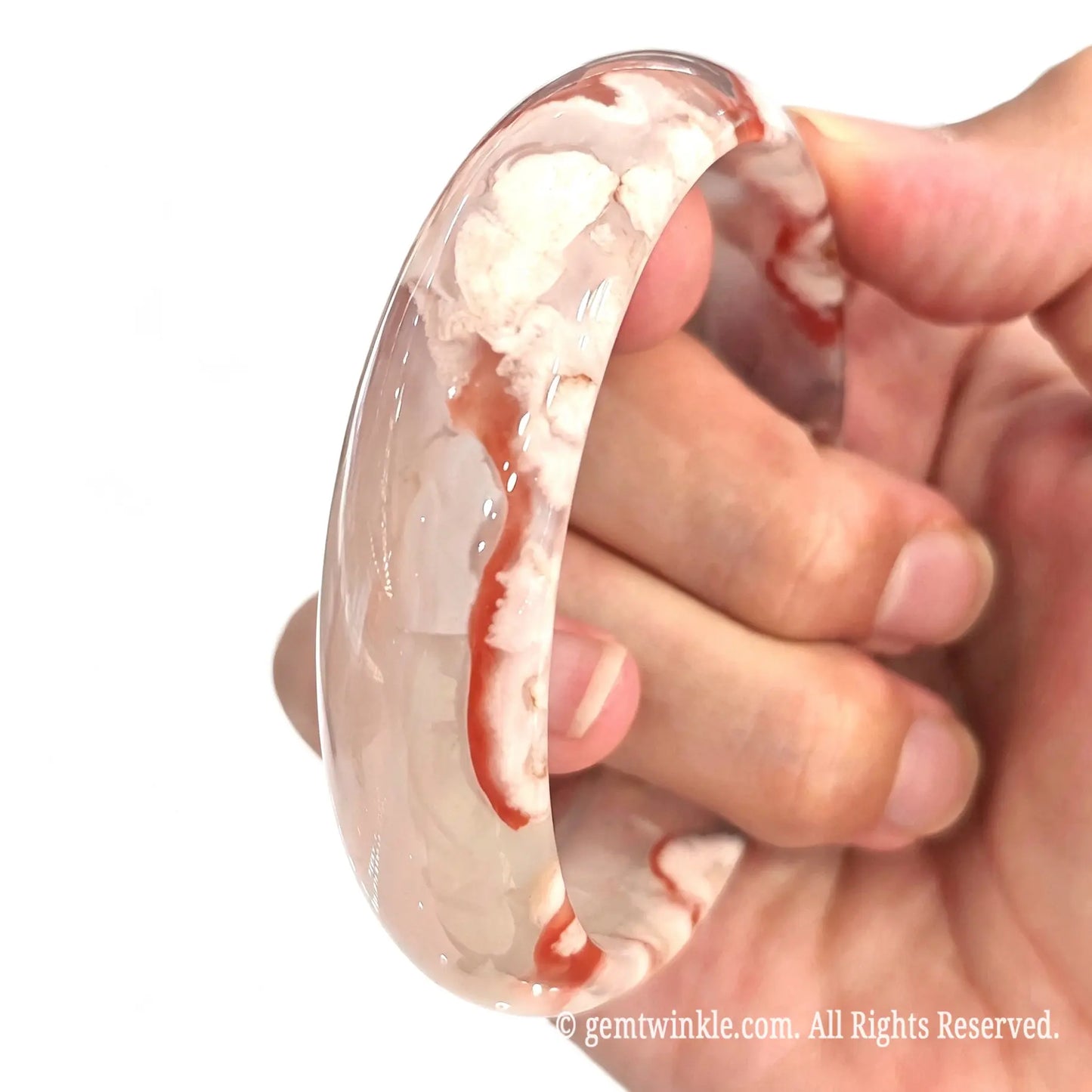 Handheld view showing the inner band profile and smooth surface finish of the cherry blossom agate bangle