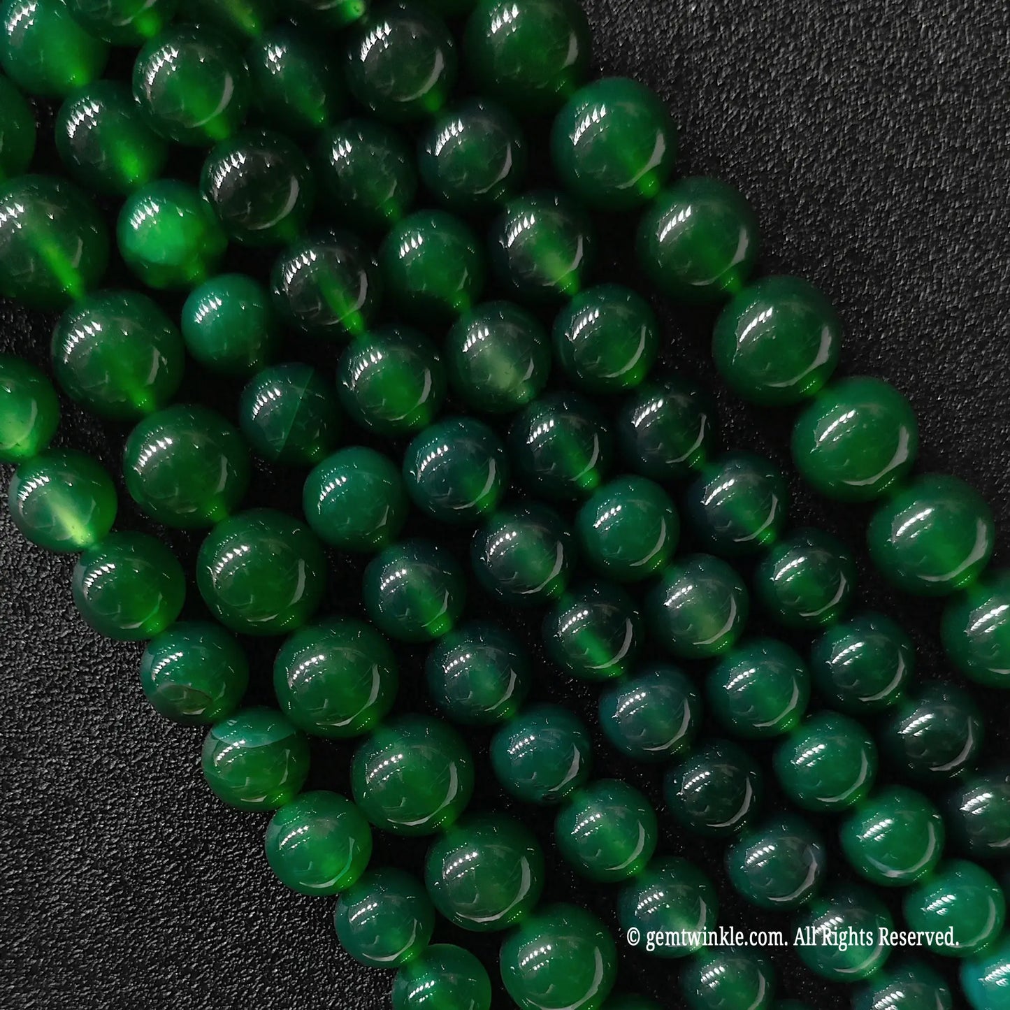 Multiple strands of green agate round beads held in hand for scale and size range verification