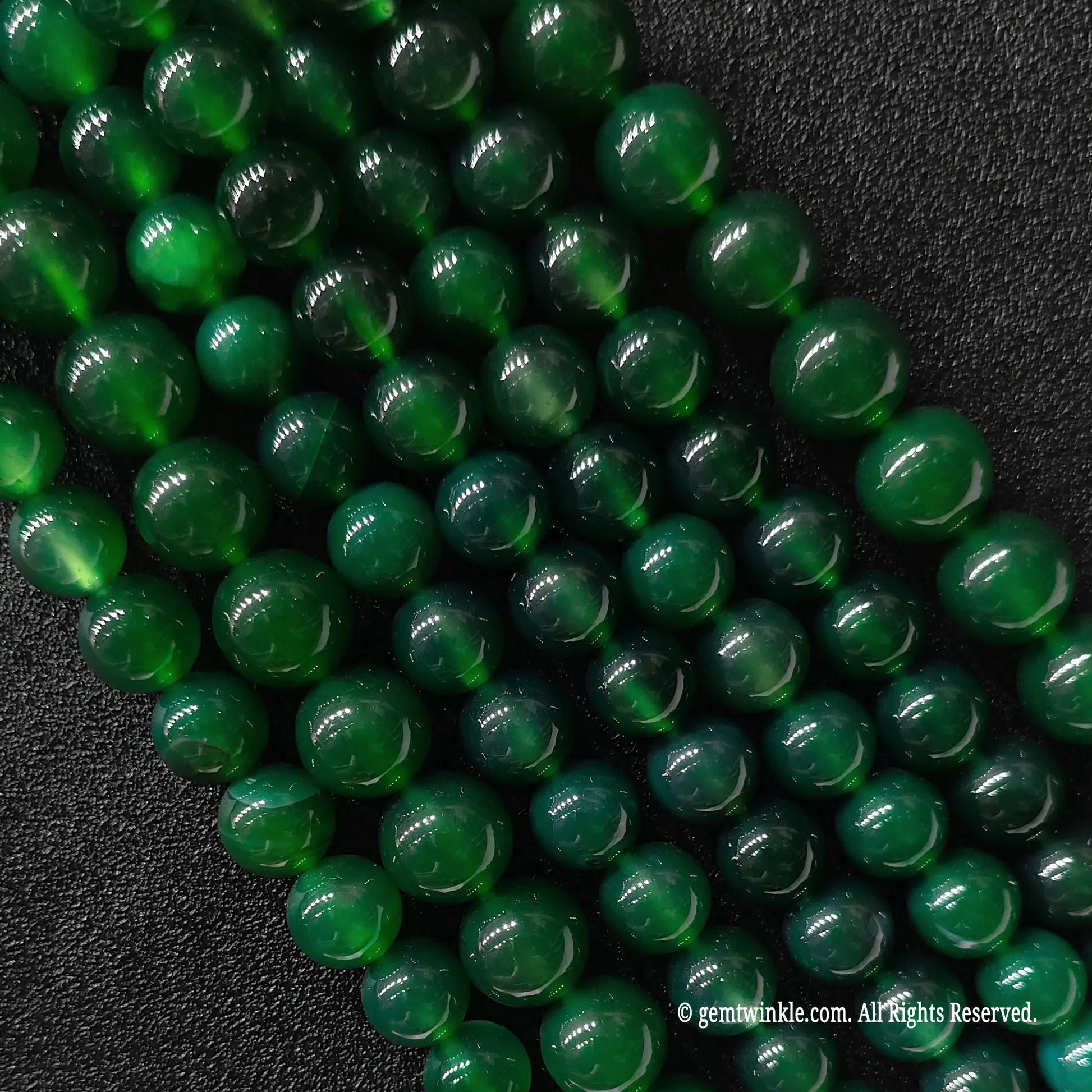 Multiple strands of green agate round beads held in hand for scale and size range verification